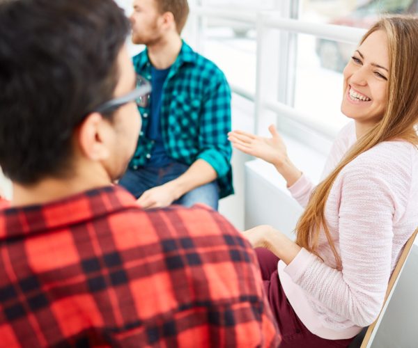 Happy girl smiling at her classmate during conversation